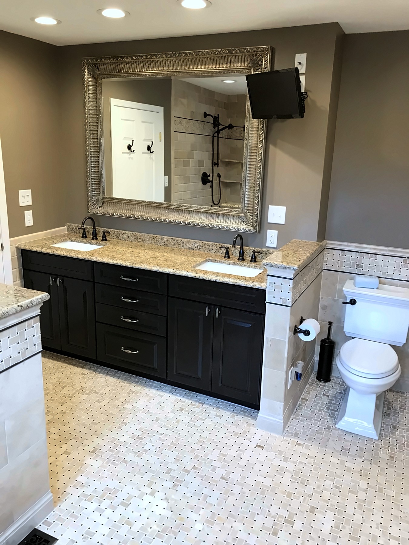Bathroom with dark double vanity and framed mirror