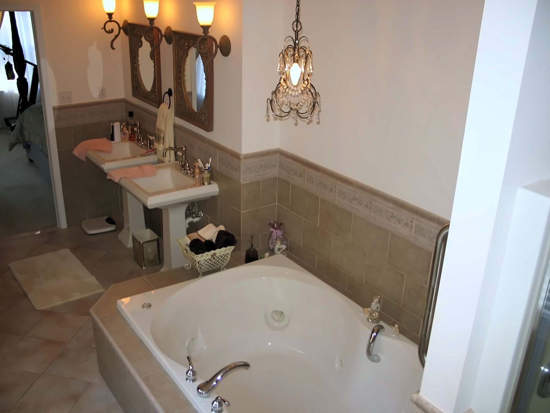 Bathroom with soaking tub, pedestal sinks and chandelier