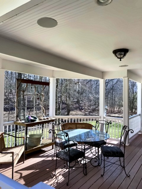 Covered porch with dining set, ceiling fan and white railings