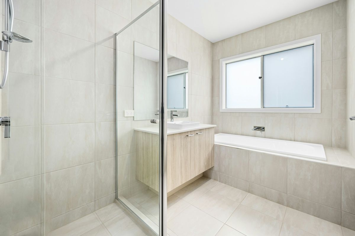Light tile bathroom with frameless glass shower door – – Ocean City home remodeling