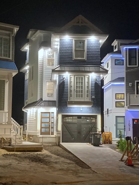 Three-story shore home with balcony and garage lit at night