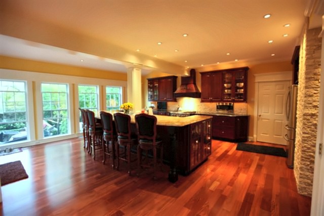 Portfolio photo: Open kitchen with hardwood floors, island seating and stone accent wall