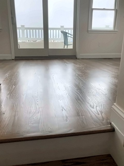 Refinished hardwood floor leading to French doors and a deck