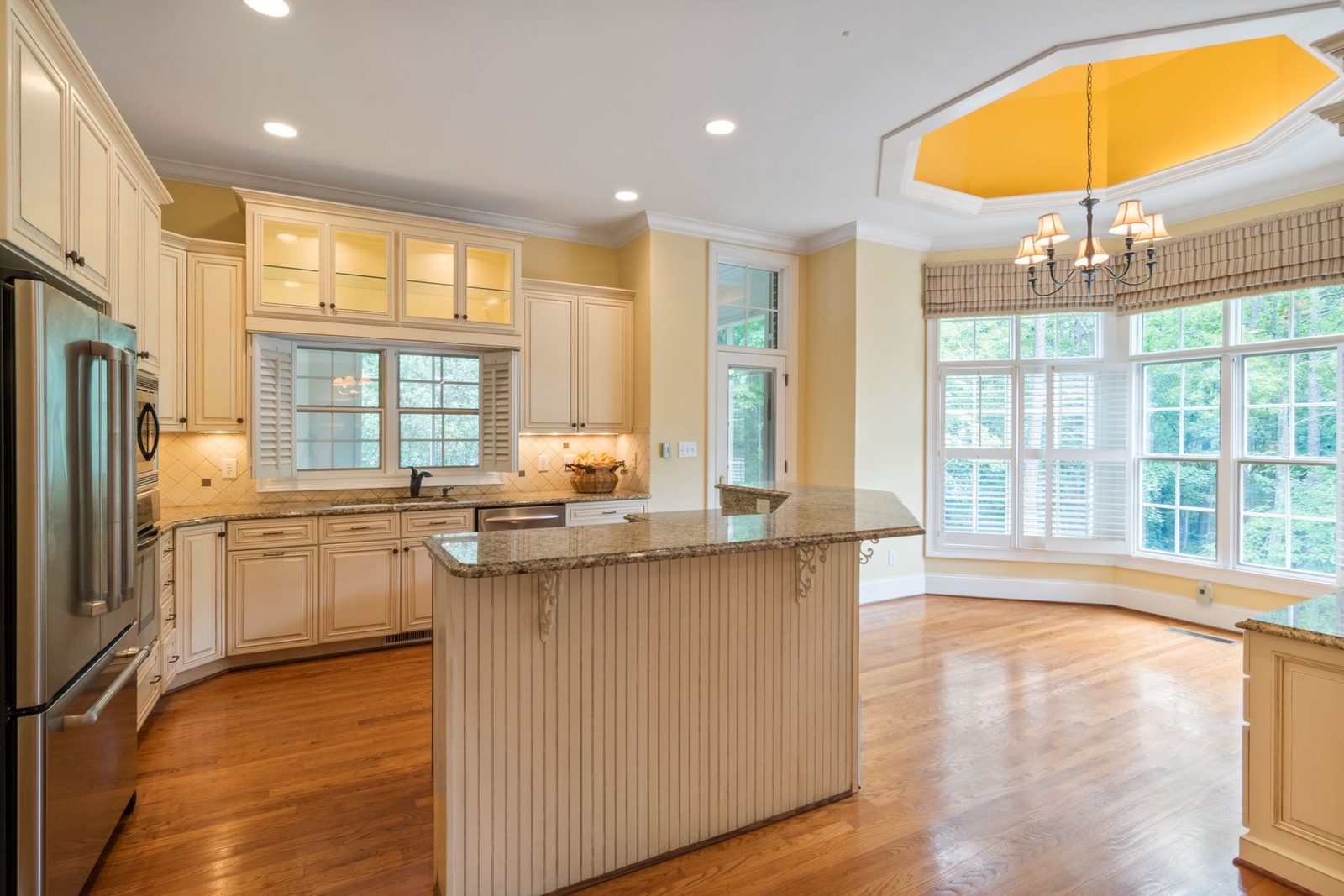Spacious kitchen with cream cabinets, granite island and large windows – gallery