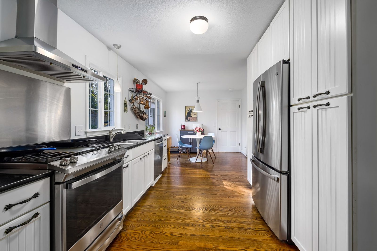Spacious kitchen with white cabinets and wood flooring