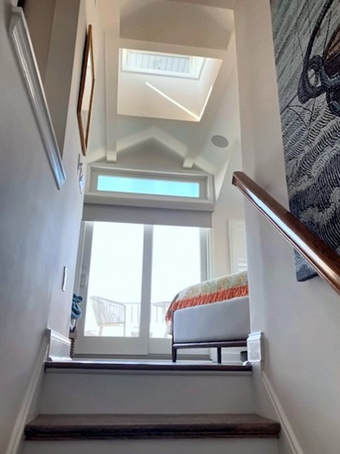 Stairway leading to a bright room with skylight and transom window