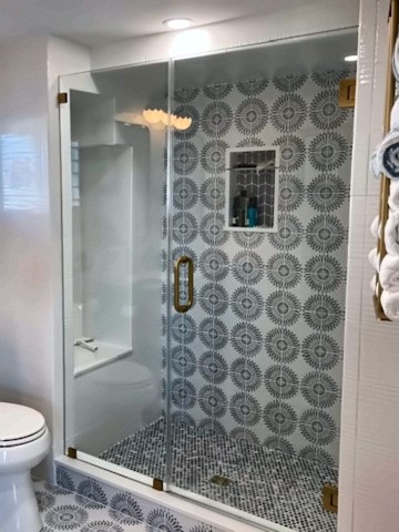 Walk-in shower with patterned tile wall, niche and brushed brass fixtures