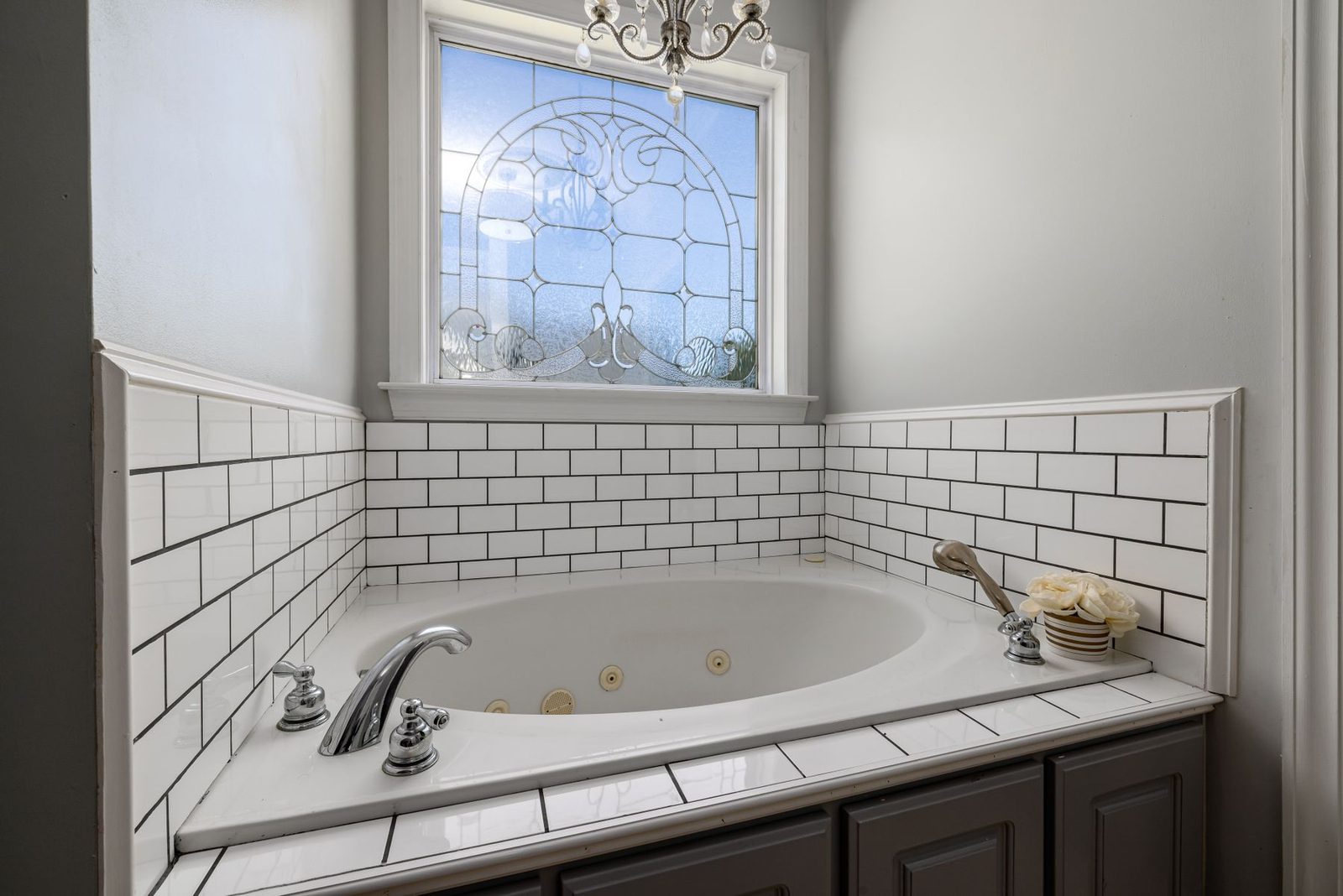 White tiled bathroom with soaking tub under a window – gallery